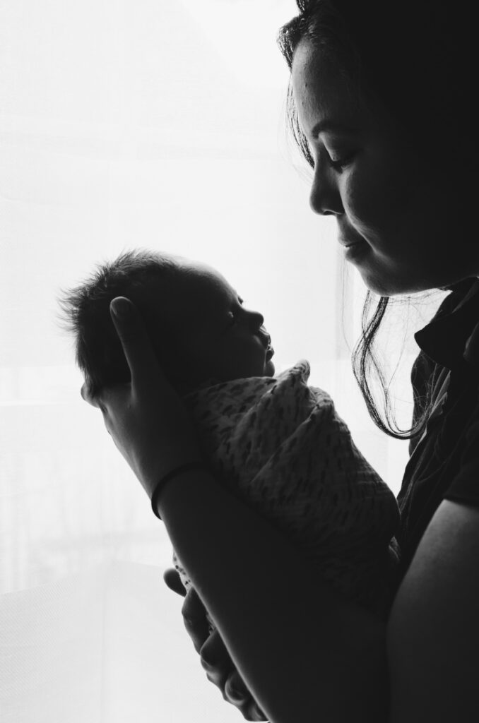 A swaddled child being held by a woman